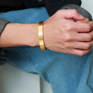 Close-up of a minimalist gold stainless steel open bangle worn on a man's wrist