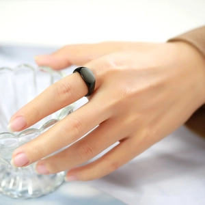 Close-up of minimalist black signet ring with glossy finish worn on index finger
