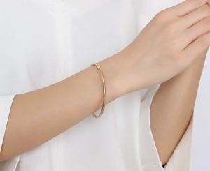 Detail of elegant 18k rose gold plated slim stainless steel bangle worn on wrist