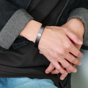 Close-up of a minimalist black polished stainless steel cuff bracelet worn by a man
