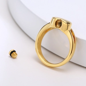 Macro detail of golden cremation ring showing threaded opening and sealing screw