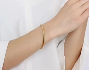 Close-up of minimalist golden titanium steel bangle worn on wrist with mirror finish