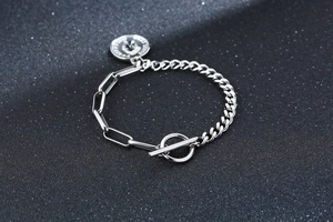 Vue détaillée du bracelet à maillons argentés avec fermoir à bascule et pendentif couronne