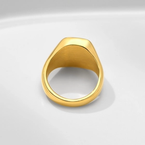 Polished gold stainless steel star signet ring displayed on a modern white ceramic tray