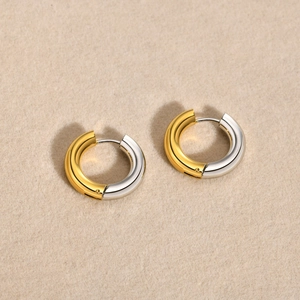 Detail of two-tone gold and silver hoop earrings with a polished metallic finish