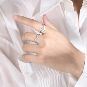 Detailed view of stacked V-shaped silver rings with cubic zirconia inlay on model's hand