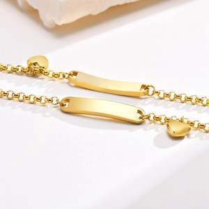 Macro detail of gold stainless steel ID bracelets with heart charms and engravable plates