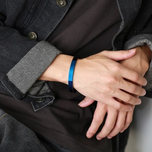 Detailed view of a gradient blue-black stainless steel open cuff bangle on a male wrist