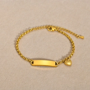 Detailed view of gold stainless steel bracelet featuring an ID plate and heart charm