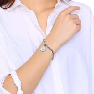 Détail du pendentif pièce Elizabeth sur un bracelet en chaîne d'acier argenté poli