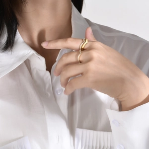 Détail d'une bague dorée ondulée avec zircons portés au doigt pour un style élégant
