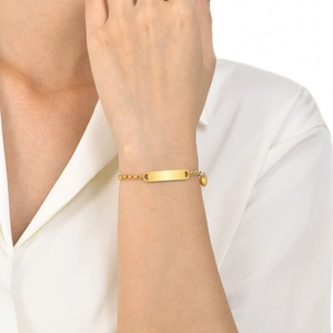 Close-up of a gold heart charm bracelet on a model wrist with a rectangle plate