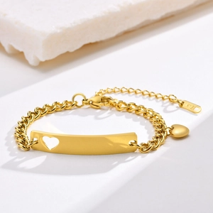 Detailed shot of gold heart bracelet with K18 engraved tag on white stone