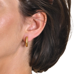 Minimalist gold plated stainless steel huggie hoop earrings worn by a model