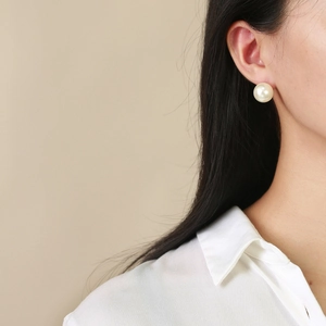Gros plan de boucles d'oreilles minimalistes en perles de verre portées par un mannequin