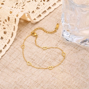 Detail of gold stainless steel anklet showing five hollow heart charms and lobster clasp
