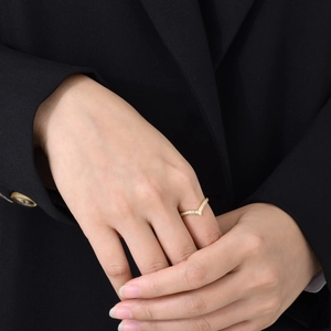 Fashionable gold V-shaped ring with zircon stones worn on hand with black background