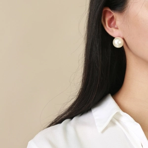 Gros plan d'une grande boucle d'oreille en perle de verre blanche au design minimaliste