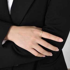 Gros plan d'une bague en V dorée avec zircons portée par un mannequin en tenue de bureau