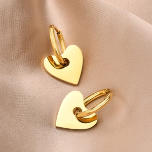 Boucles d'oreilles créoles cœur en acier doré poli sur fond de soie couleur champagne