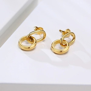 Détail de boucles d'oreilles double anneau doré en titane sur une surface géométrique