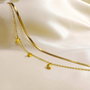 Detail of double-layer gold anklet with star, moon, and heart charms on silk cloth