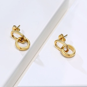 Détail macro de boucles d'oreilles dorées entrelacées avec poinçon en argent S925 poli