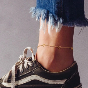 Gold stainless steel anklet with hollow heart charms on woman's ankle with street fashion