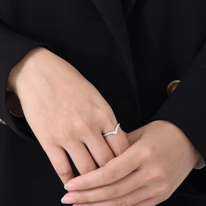 Gros plan d'une bague élégante en V en argent sertie de zircons sur le doigt