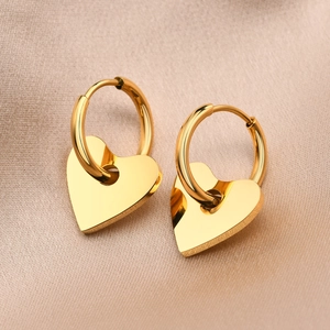Boucles d'oreilles cœur dorées polies présentées sur un tissu élégant en soie champagne