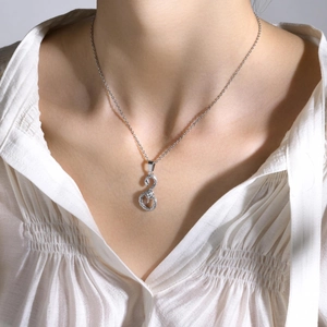 Primo piano di una collana con ciondolo a serpente d'argento su camicia di seta
