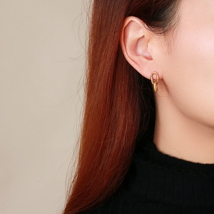 Gros plan d'élégantes boucles d'oreilles doubles anneaux dorées portées par un mannequin
