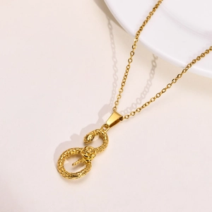 Vista macro della collana con pendente a serpente dorato e trama di squame con finitura di lusso