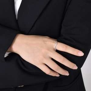 Détail d'une bague en zircon en V dorée sur une main portant une tenue de bureau noire