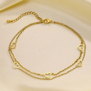 Detail shot of a double-layered golden ankle chain with five hollow heart pendants on silk