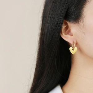 Élégantes boucles d'oreilles créoles dorées avec cœur portées par un mannequin femme