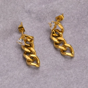 Détail de boucles d'oreilles chaîne dorées avec zircon cœur et design maille gourmette