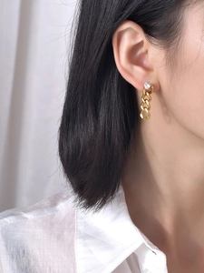 Boucles d'oreilles pendantes dorées avec cœur en zircon portées sur fond épuré