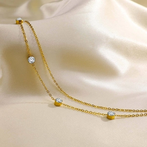 Macro shot of gold double-layer anklet with clear bezel-set zircons on silk background