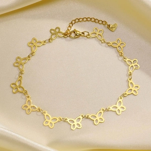 Close-up of golden stainless steel hollow butterfly anklet on champagne satin fabric
