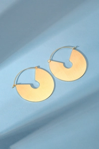 Gros plan de boucles d'oreilles dorées en éventail avec texture en métal brossé fin