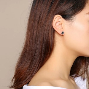 Close-up of Ace of Spades stud earring worn by a model in titanium steel style