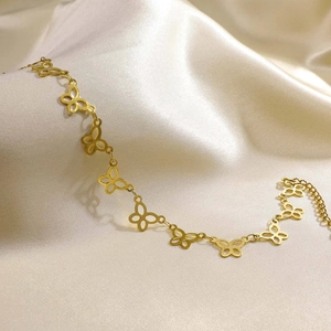 Close-up of golden hollow butterfly anklet with adjustable chain on champagne satin