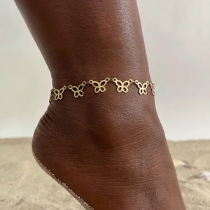 Elegant gold butterfly anklet featuring hollow charms on a beach vacation background