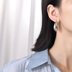 Silver hollow teardrop hoop earrings for women with high-polish mirror finish on model