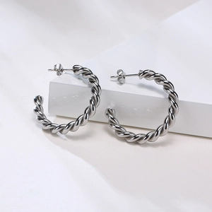 Détail de boucles d'oreilles créoles torsadées argentées en forme de C poli