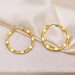 Detailed view of large gold hoop earrings featuring a unique hammered scalloped edge design