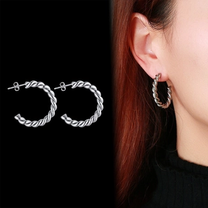 Détail de boucles d'oreilles créoles en C torsadées argentées et vue portée du bijou