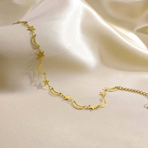 Detail of gold double-layer star and moon anklet on champagne satin background