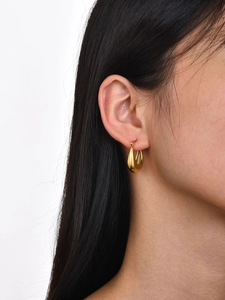 Gros plan d'un modèle portant des boucles d'oreilles dorées en forme de U poli brillant